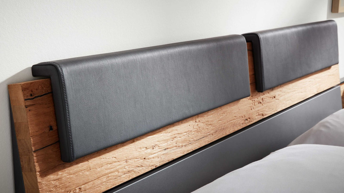 Schlafzimmer mit Doppelbett, Sitzbank und großem Kleiderschrank in Grau und Holz