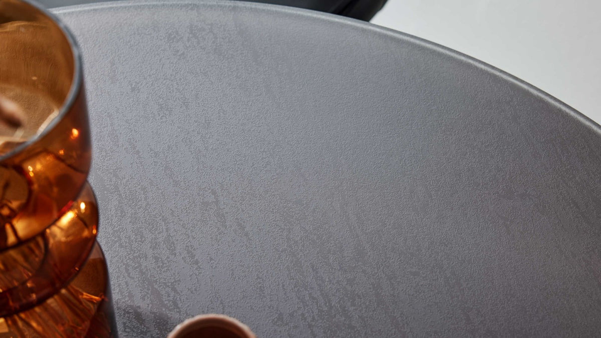 Bartisch mit runder, dunkelgrauer Platte und modernem Edelstahlgestell